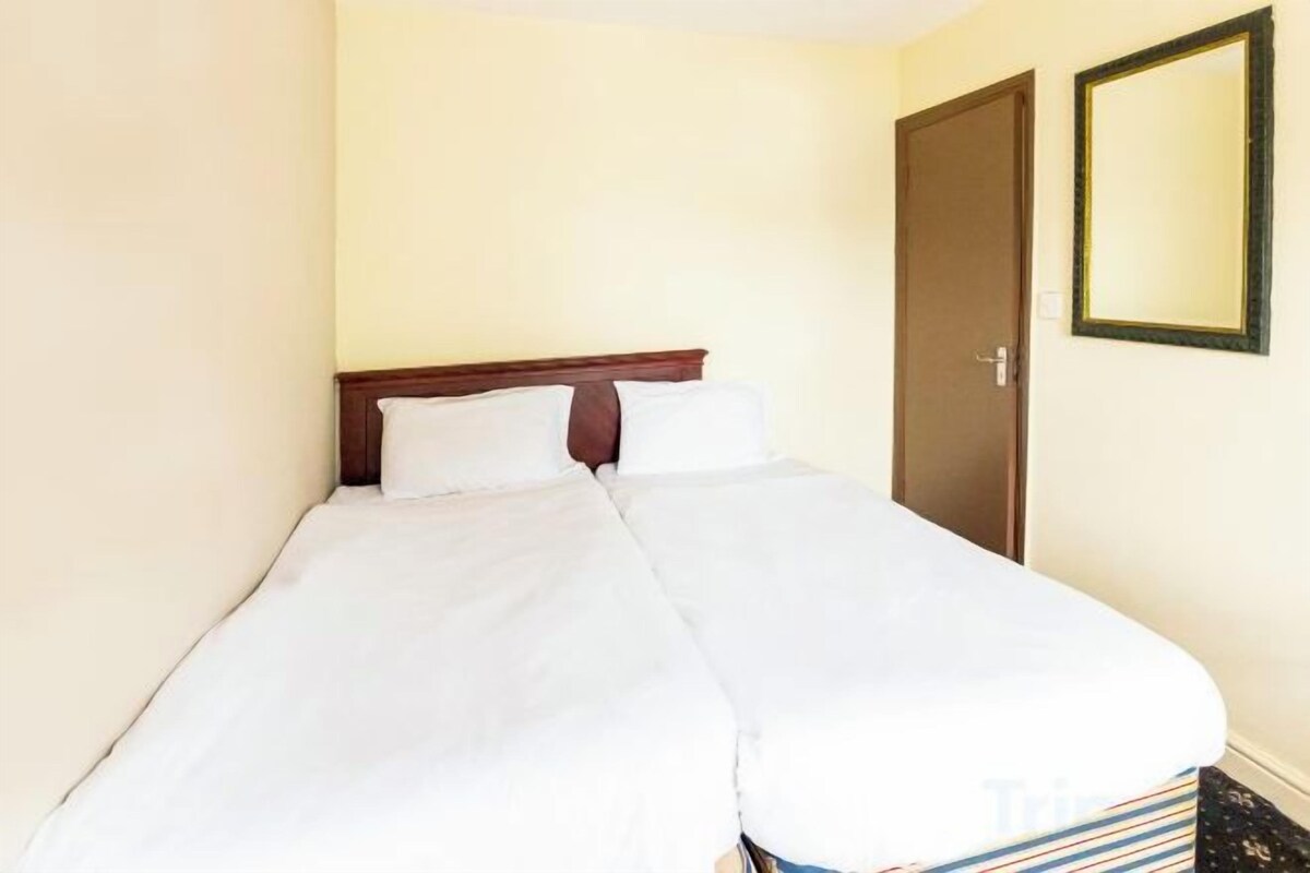 A single bed with white bedding in a room with a wooden headboard, a door, and a mirror on the wall.