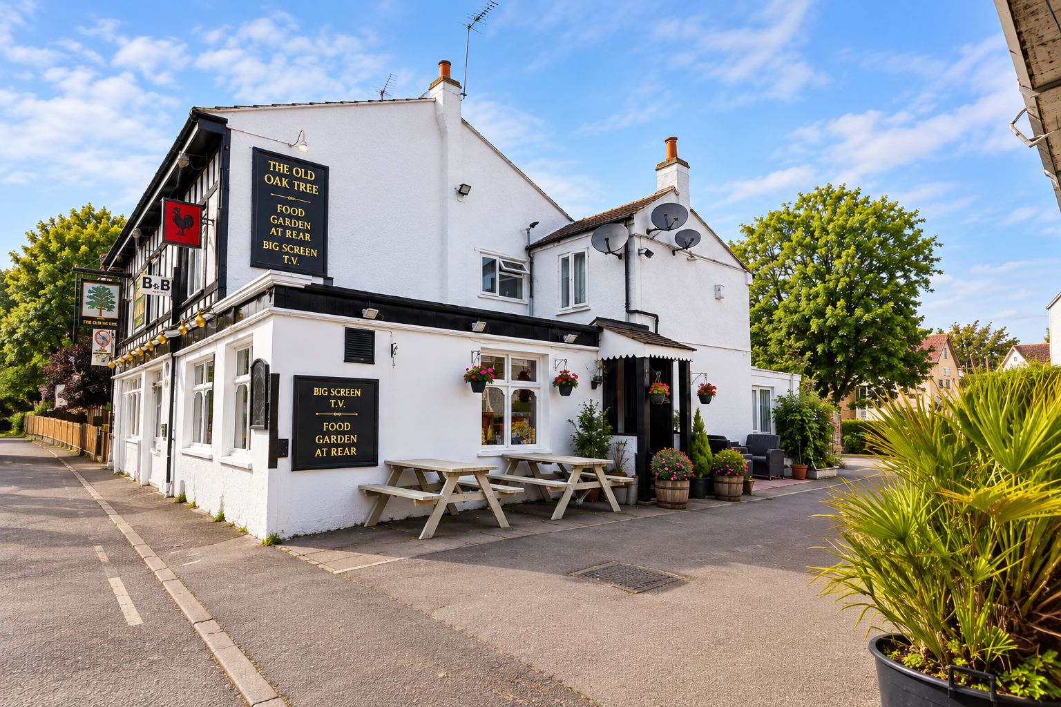 A white building with a sign indicating a pub named 'The Old Oak Tree' offering food, a garden, and a big screen TV.
