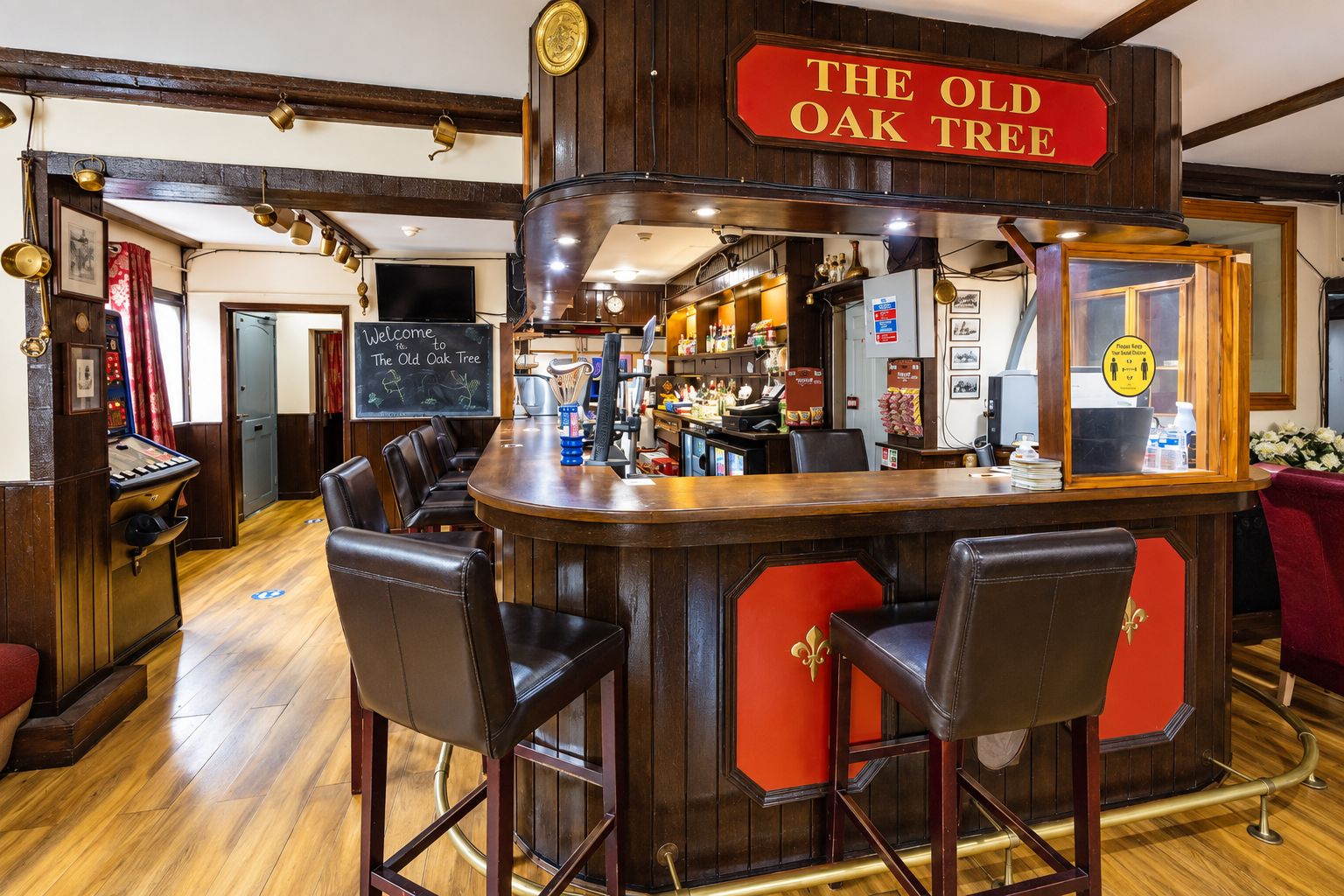 Zona de bar con un letrero que dice 'The Old Oak Tree', que incluye una barra, dos taburetes de cuero y una jukebox.