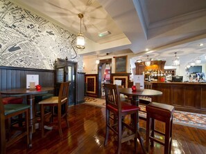 Un restaurante con mesas y sillas de madera, una zona de bar y una pared con un mapa.