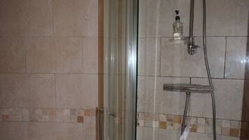 A bathroom with a glass-enclosed shower, a toilet, and a towel rack.