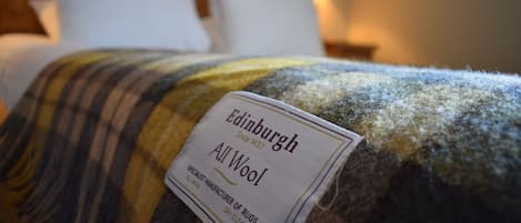 Una cama con una etiqueta que dice 'Edinburgh All Wool', indicando el material de la ropa de cama.