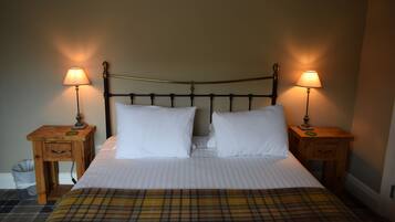 A bed with two white pillows, a plaid blanket, and two bedside tables with lamps.