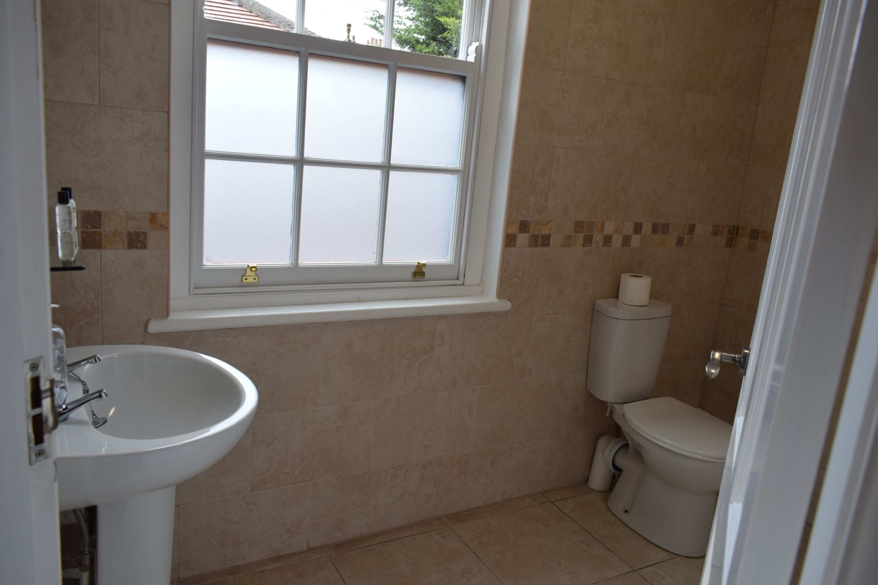 A bathroom with a white sink, a toilet, and a window.