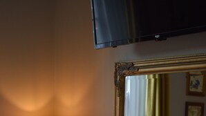 A room with a wooden desk, a lamp, a mirror, a remote control, and a menu on the wall.