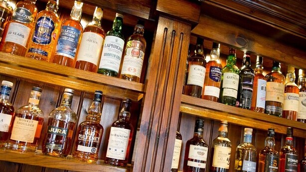 A bar with shelves stocked with various liquor bottles. - The Rose and Crown (York)