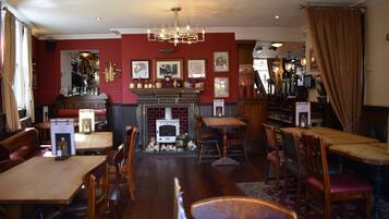 Un pub acogedor con muebles de madera, una chimenea y diversas fotos enmarcadas en las paredes.