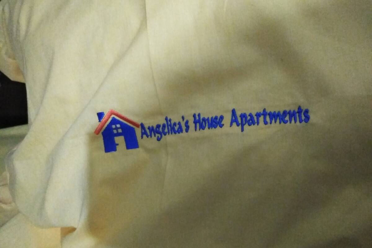 A white pillow with a logo and text reading "Angelica's House Apartments".