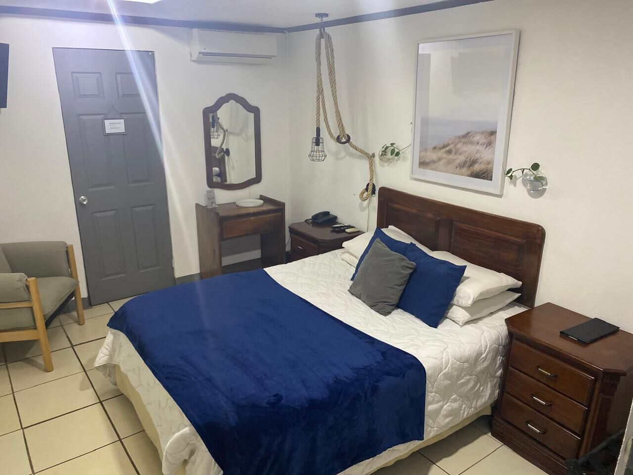 A bedroom with a bed, bedside tables, a chair, a mirror, and a framed picture on the wall.