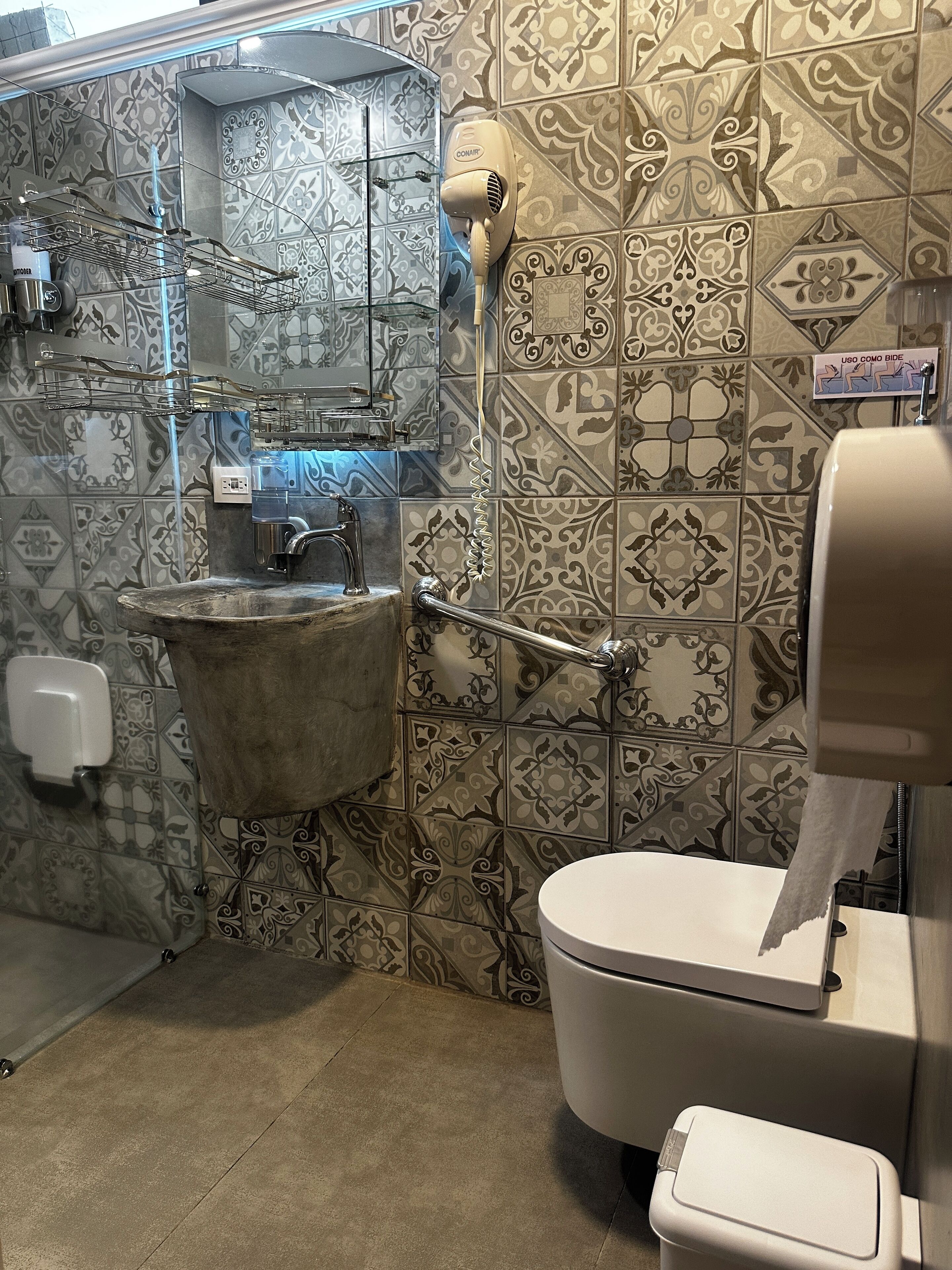 A bathroom with a sink, toilet, and hand dryer.