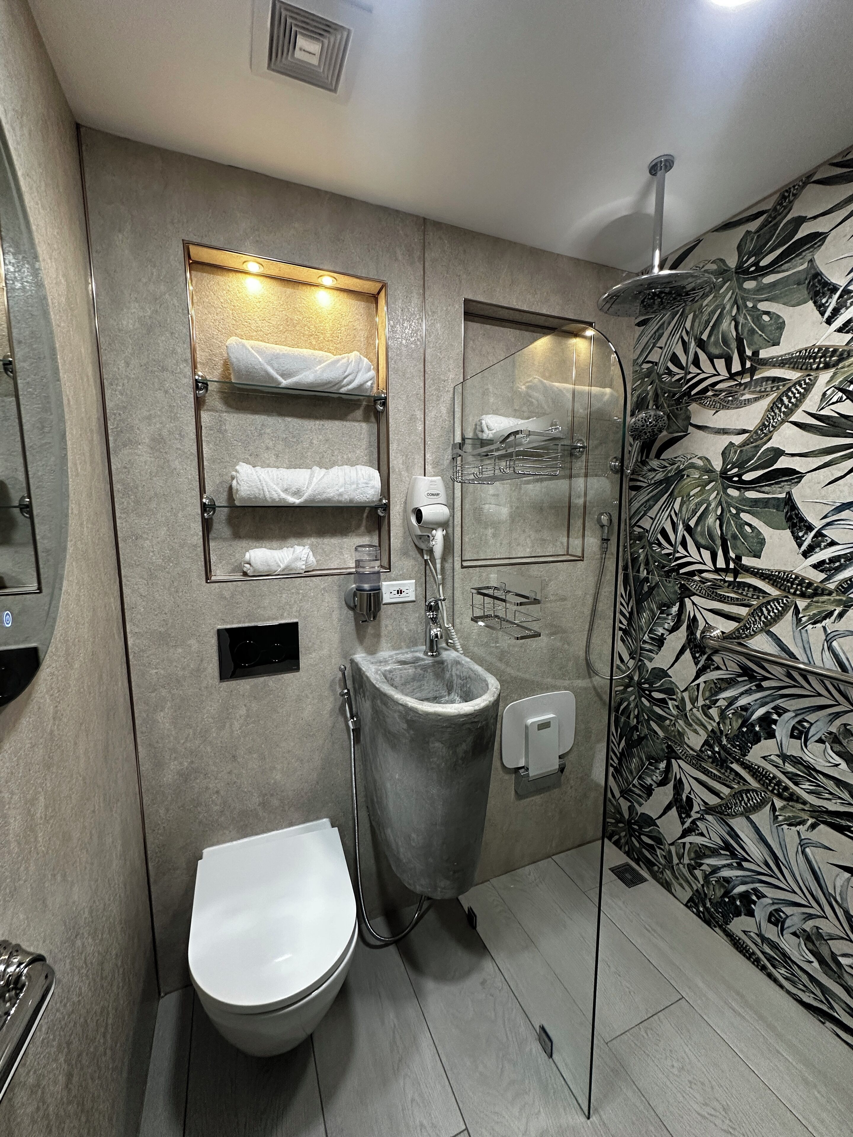 Een moderne badkamer met toilet, wastafel, douche en een handdoekhouder.
