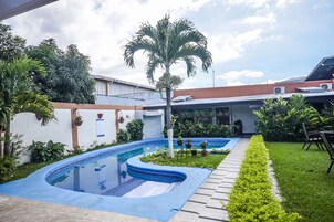 Una piscina al aire libre, sillones reclinables de piscina