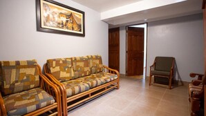 A living room with a sofa and armchairs, a wooden door, and a framed picture on the wall. - Hostal La Payacha (Machu Picchu)