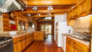 A spacious wooden cabin kitchen with a large island, wooden cabinets, and a built-in oven.