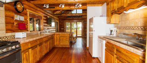 A spacious wooden cabin kitchen with a large island, wooden cabinets, and a built-in oven.