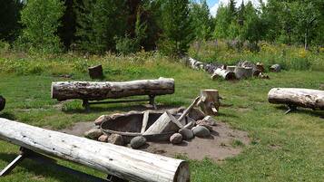 A rustic outdoor setting with logs, a wheelbarrow, and a wooden bench.