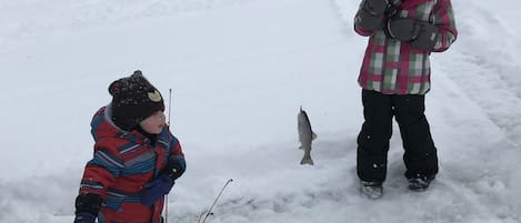 Two children fishing in a snowy outdoor setting.