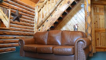A brown leather sofa in a log cabin room with a wooden staircase and a star decoration on the wall.