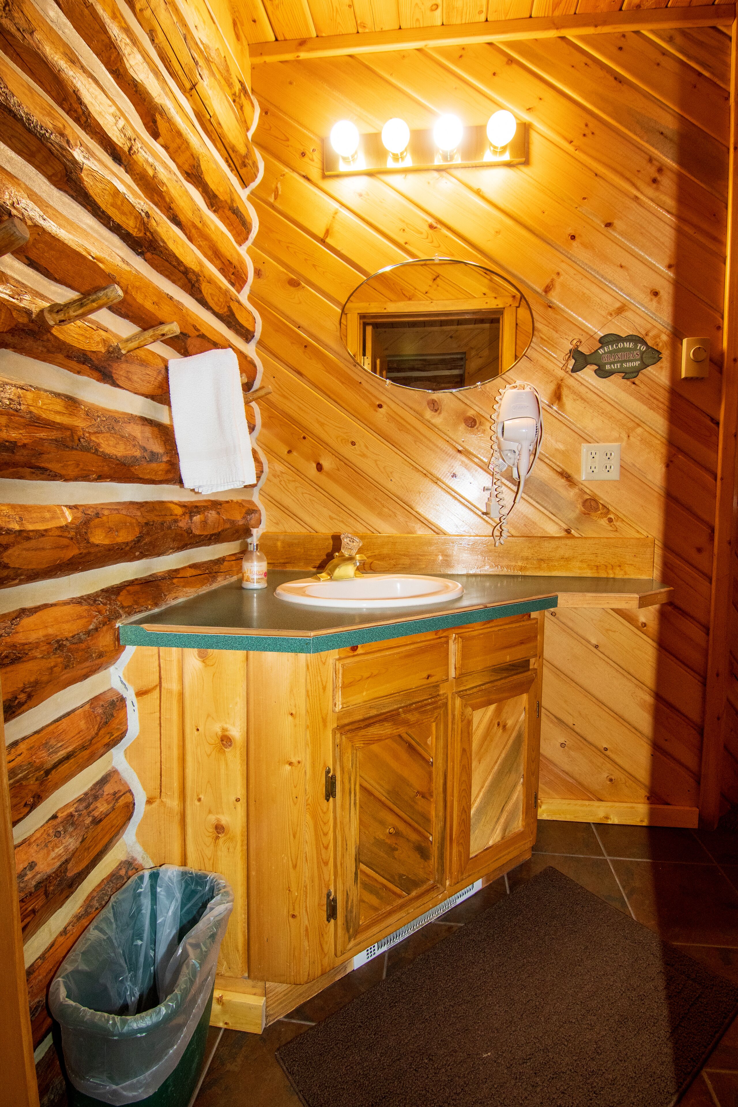Ein Badezimmer einer Holzhütte mit Waschbecken, Spiegel und Handtuch an der Wand.