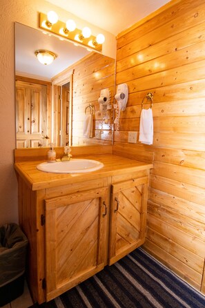 A wooden bathroom with a sink, mirror, and towel rack.