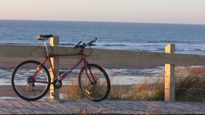 Un vélo de montagne rouge est garé sur une promenade en bois, au bord de l’océan.
