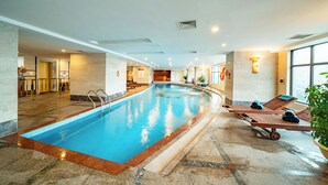 Ein Innenpool mit glatter Wasseroberfläche, umgeben von Liegestühlen und einem gefliesten Boden.