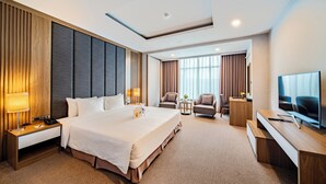 Ein modernes Hotelzimmer mit einem großen Bett, Nachttischen, einem Schreibtisch und einem Fernseher.