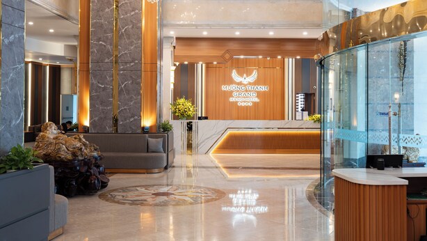 Eine moderne Hotelhalle mit einer Rezeption, einer Chandelierleuchtre und einer Sitzecke.