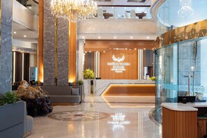 Un moderno vestíbulo de hotel con mostrador de recepción, una araña y un área de descanso.