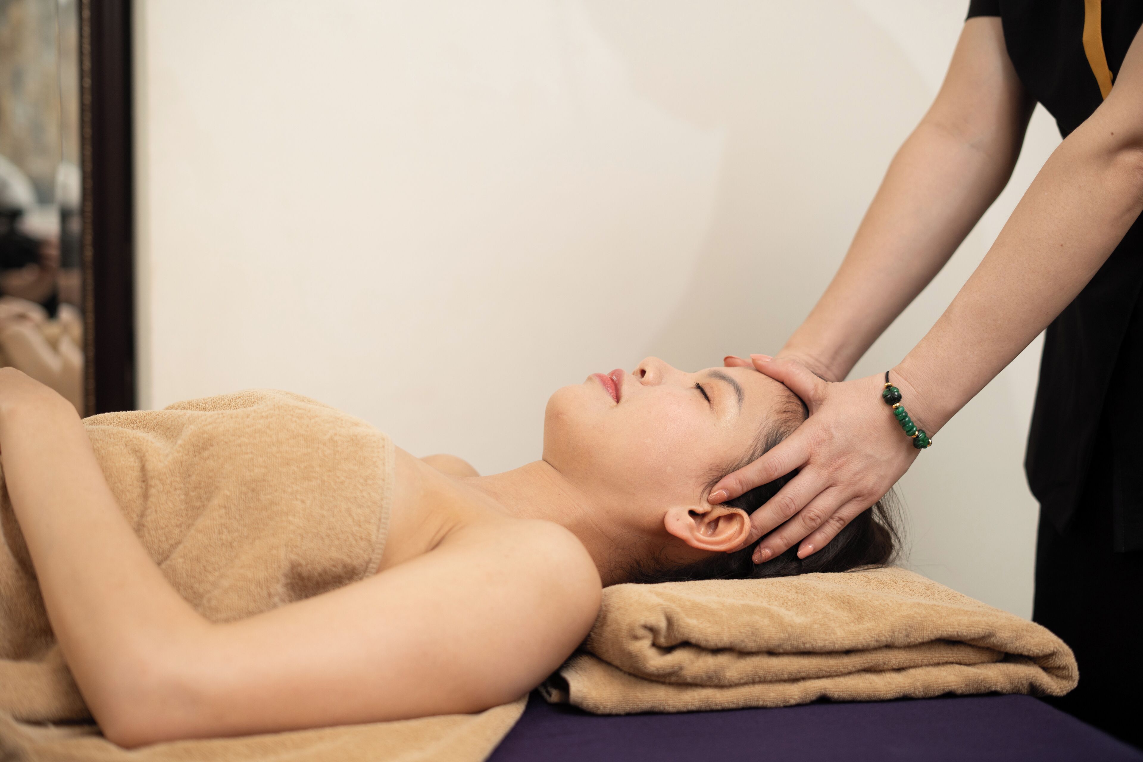 A person lying on a massage table with a towel covering their upper body.