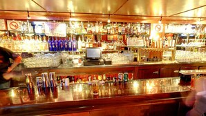 Un bar con varias botellas de licor y vasos en estantes.