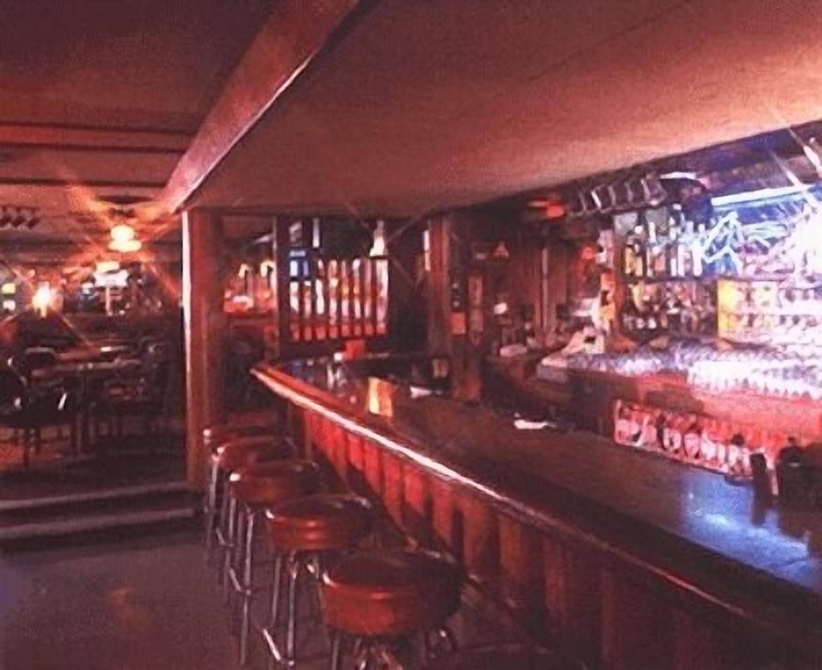 Eine Bar mit Hockern, Flaschen und einer Theke.