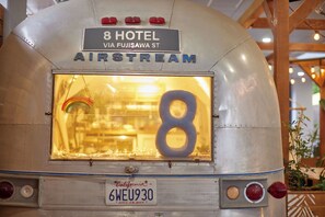 Un autobus d’époque, arborant une plaque indiquant « 8 HOTEL VIA FUJISAWA ST AIRSTREAM » et portant une plaque d’immatriculation californienne « 6WEU930 ».