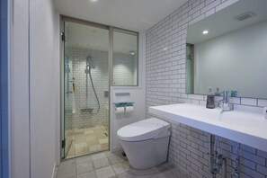 Une salle de bain moderne avec une douche à l’italienne en verre, des carreaux blancs, des toilettes blanches et un lavabo blanc avec un miroir au-dessus.