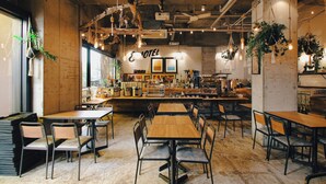 A cozy cafe with wooden tables and chairs, a bar area, and various plants and decorations. - 8Hotel (Fujisawa)