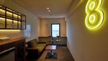 Un espacio habitable compacto con kitchenette, un sofá, una mesita y un letrero de neón con el número 8.