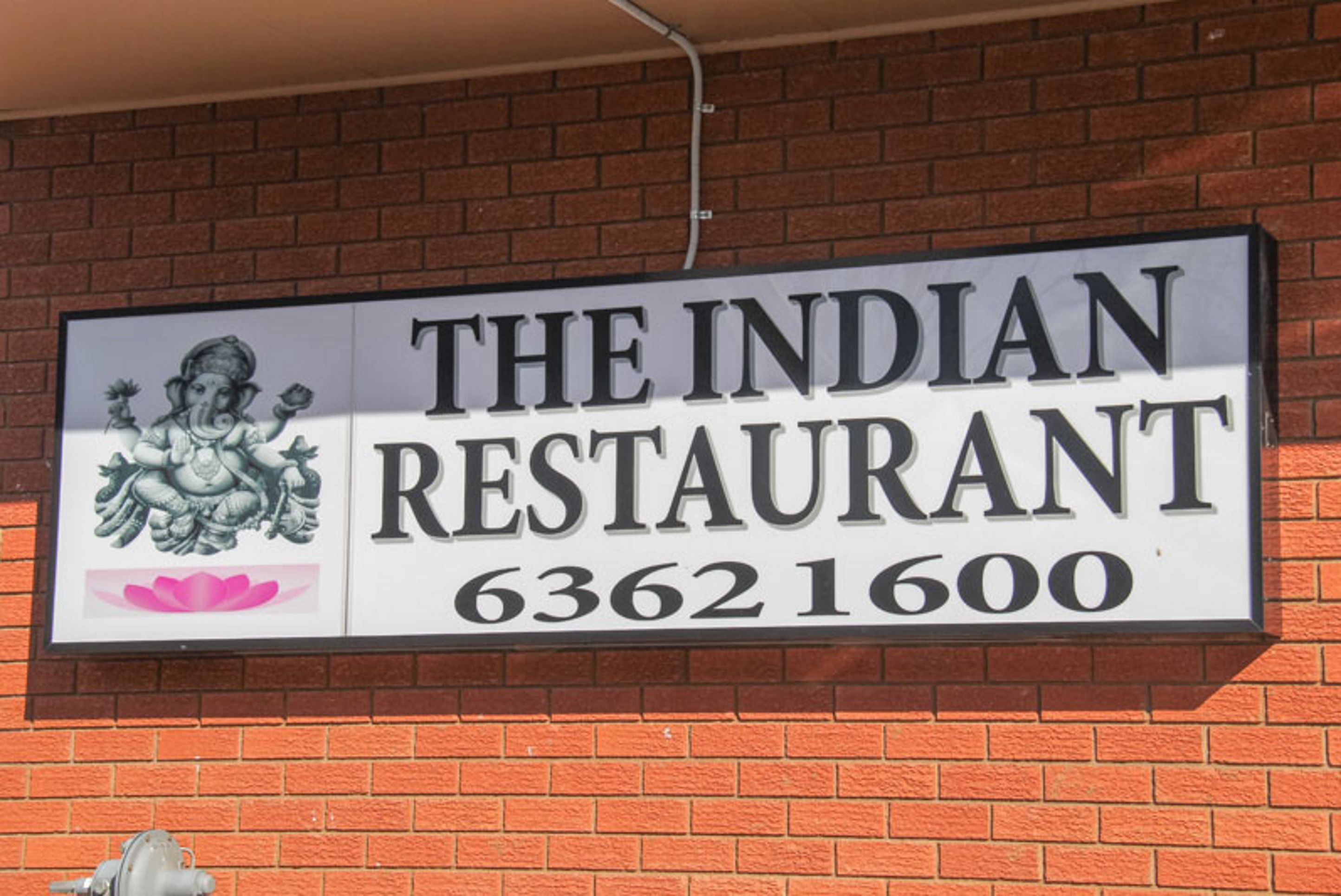Letrero que indica 'The Indian Restaurant' con el número 63621600.