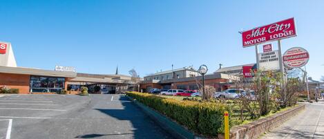 Un motel avec une enseigne indiquant « Mid-City Motel & Lodge » et « Restaurant indien et australien », et un parking situé devant.