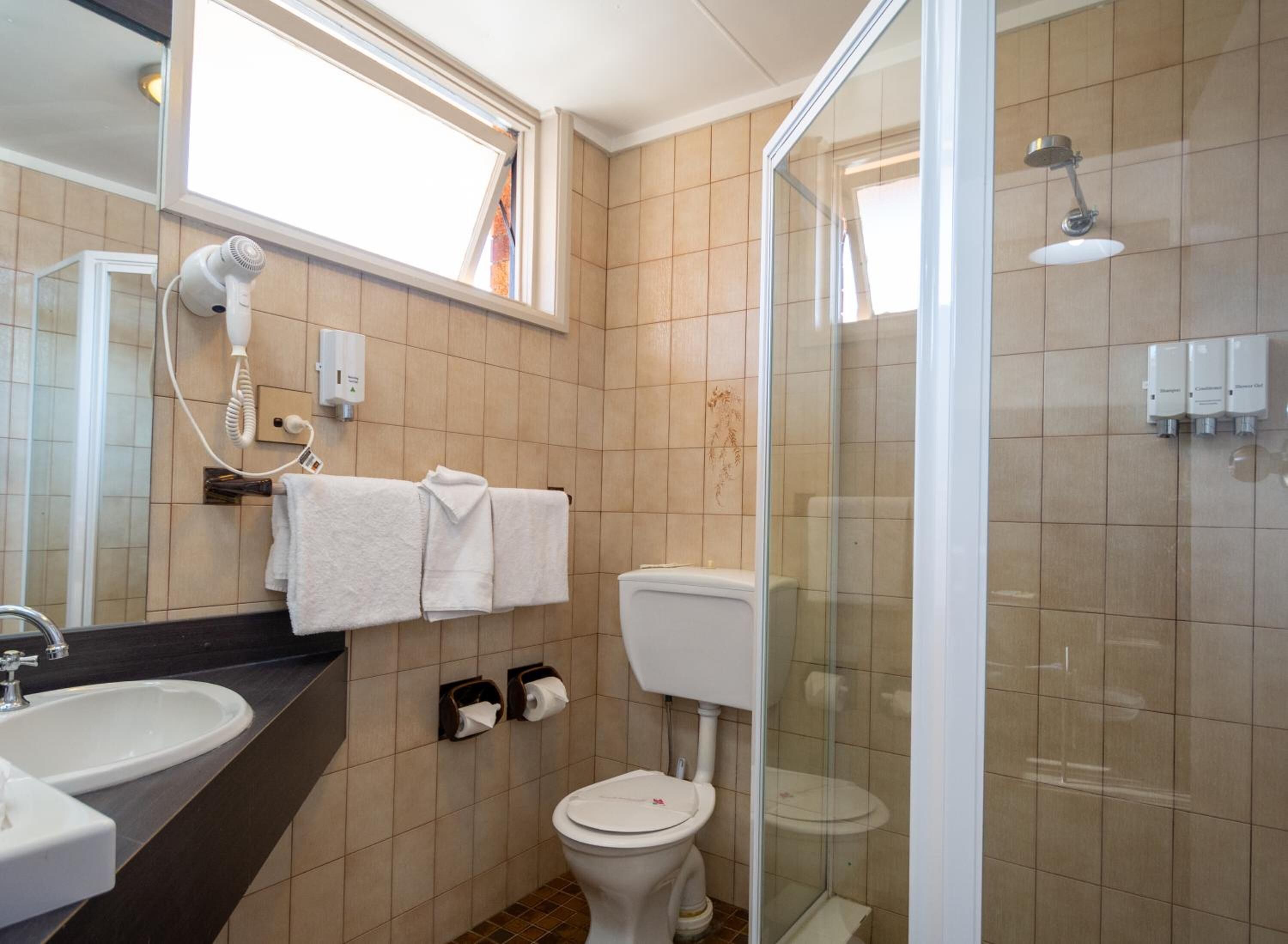 Een moderne badkamer met douche, toilet en wastafel.