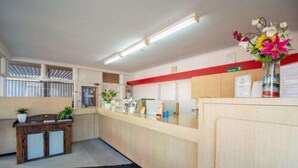 A reception area with a wooden counter, a small cabinet with glass doors, and a vase with flowers.