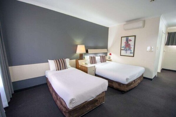 Une chambre d’hôtel avec deux lits, une table de chevet, une lampe et un tableau au mur.