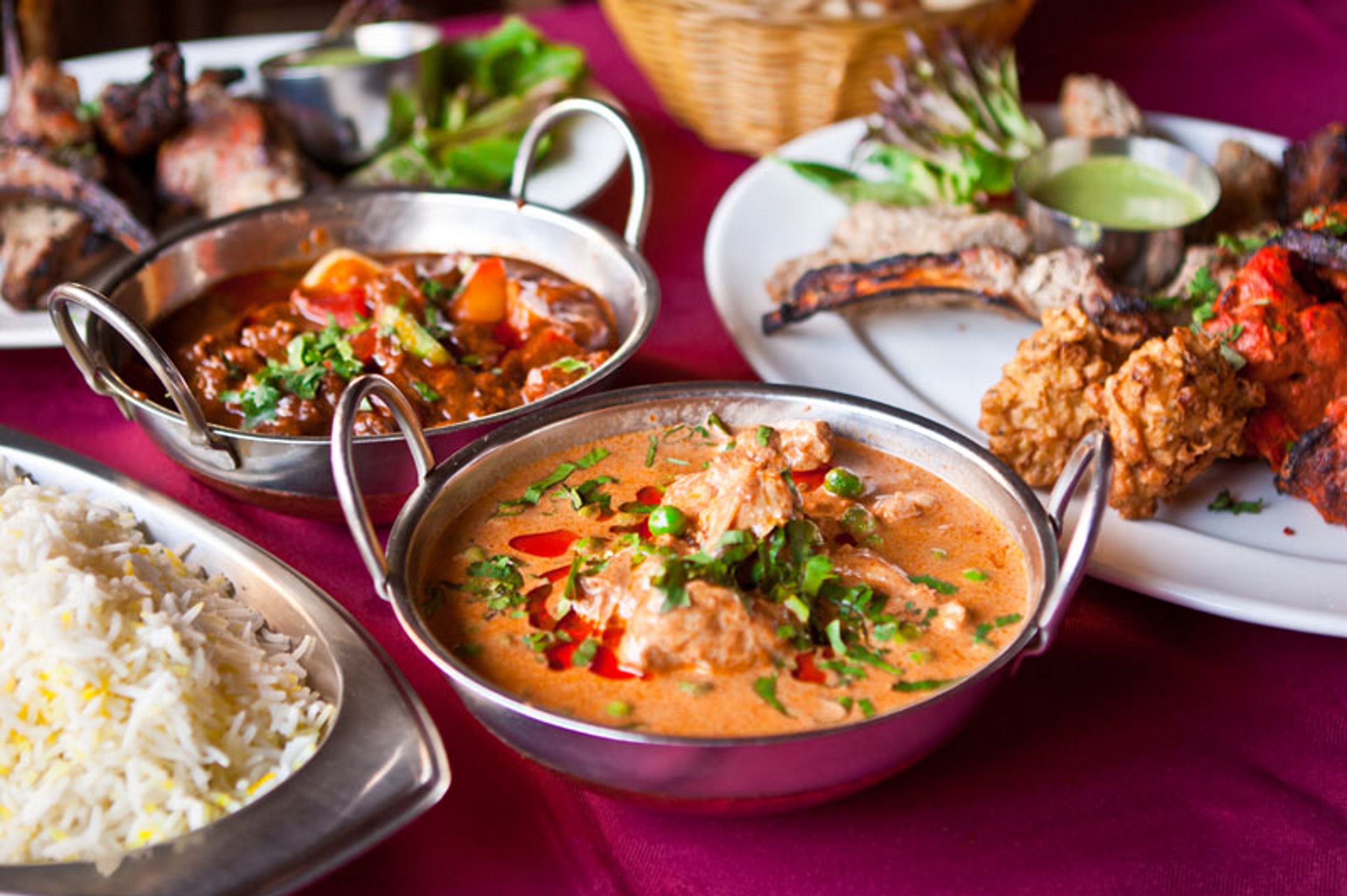 A variety of dishes including a bowl of curry, grilled meats, and rice, suggesting a diverse meal selection.