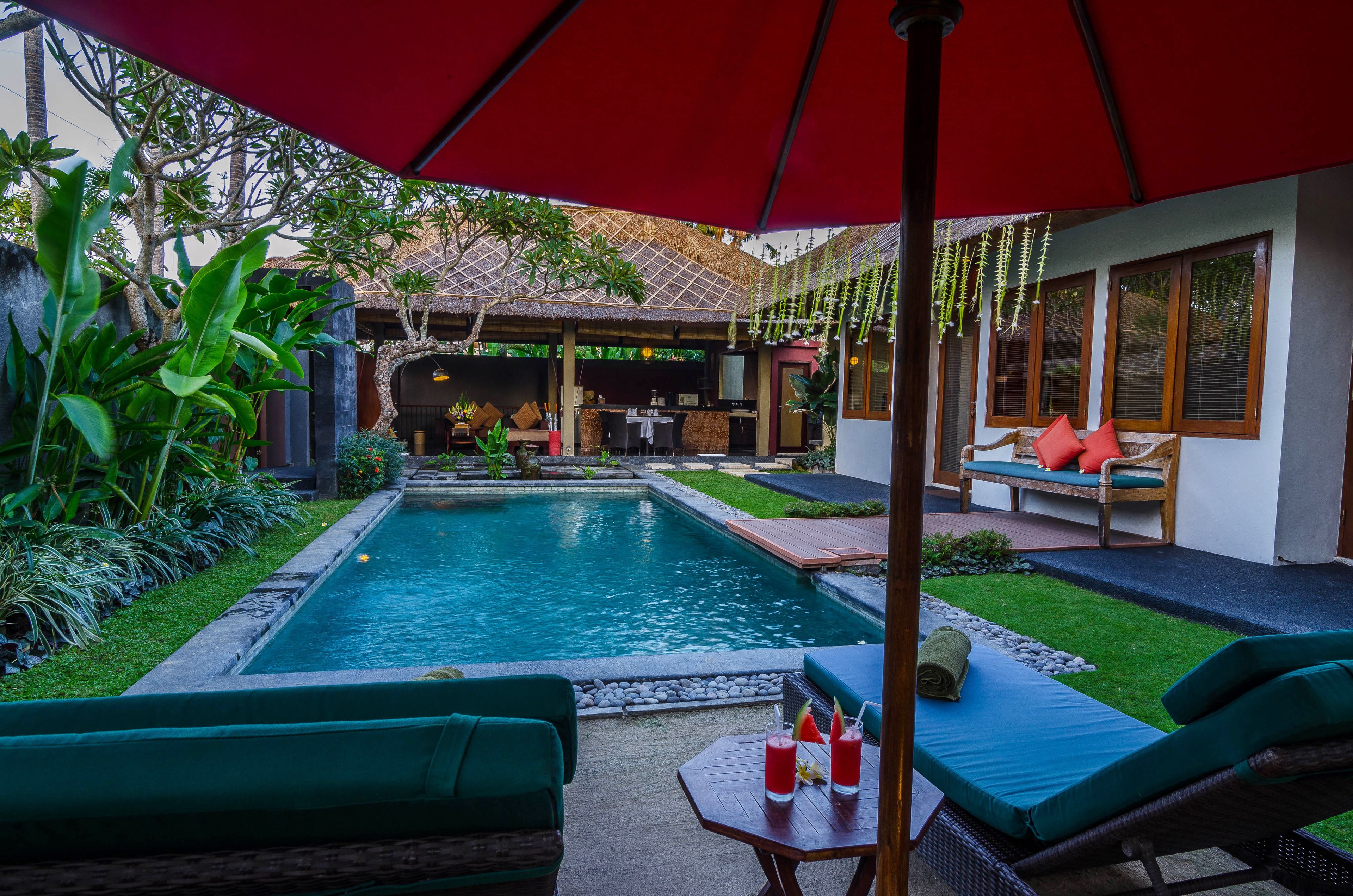 A poolside area with lounge chairs, a table with drinks, and a covered seating area.