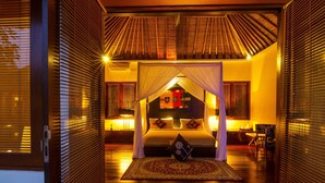 A well-lit bedroom with a canopy bed, a nightstand, and a chair. - Imani Villas (Kerobokan)