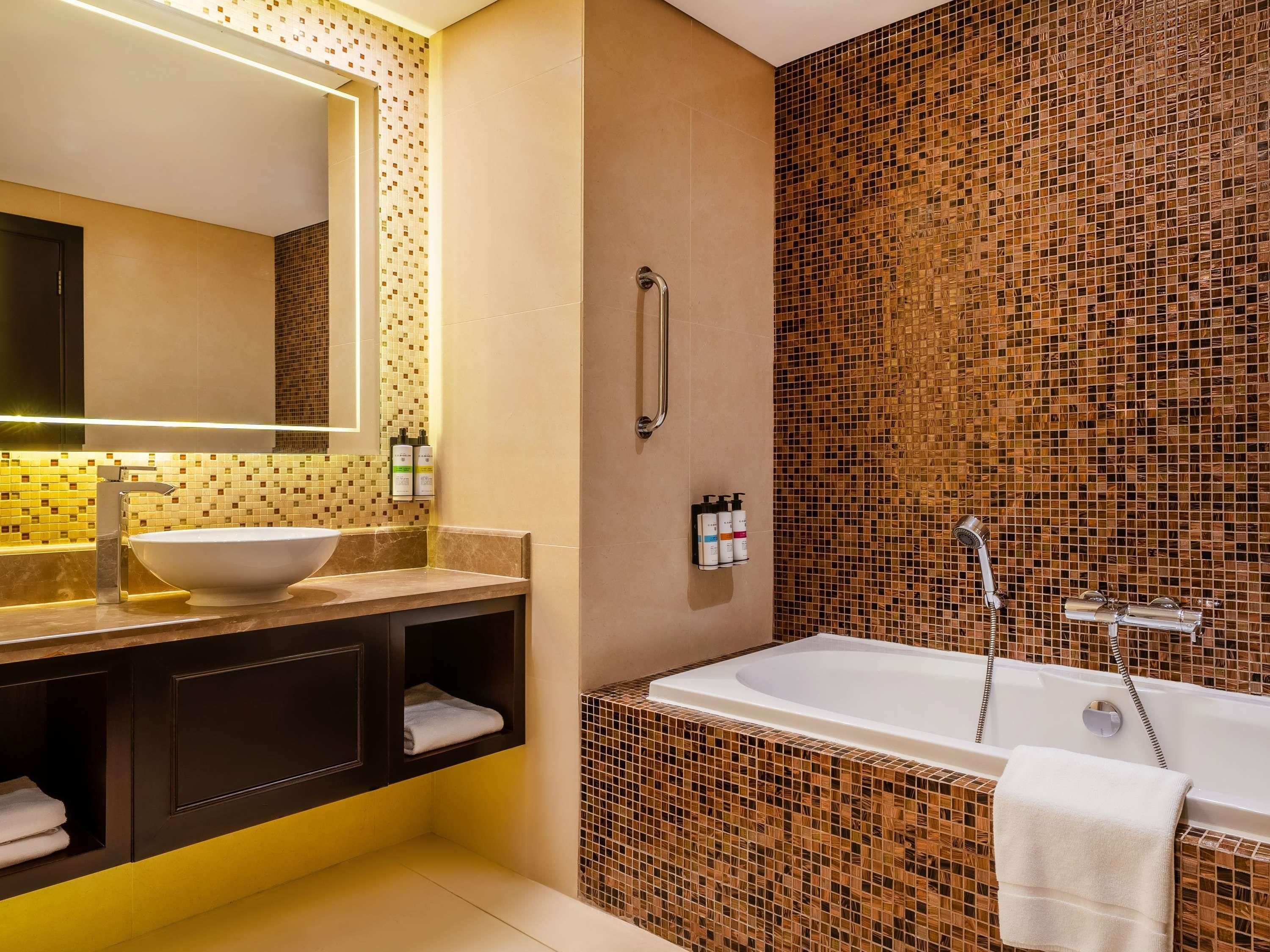 A modern bathroom with a large sink, mirror, and bathtub.