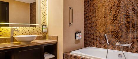 A modern bathroom with a large sink, mirror, and bathtub.