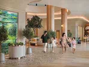 A modern lobby with a large abstract painting, a reception desk, and a seating area with a sofa and chairs.