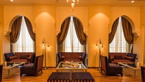 A spacious lobby with three sofas, a coffee table, and a chandelier.