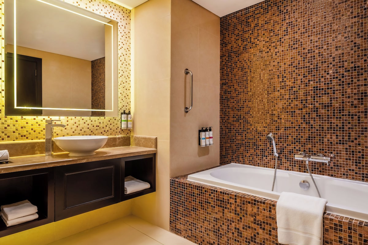 A modern bathroom with a large mirror, a sink, a bathtub, and a shower.