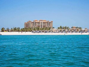 Un hotel sulla spiaggia con numerosi balconi, una spiaggia sabbiosa e un mare cristallino.